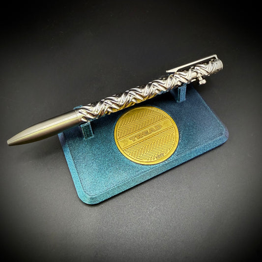 Metallic pen with a gold circular emblem on a dark background